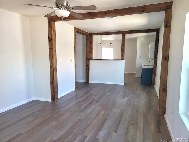 unfurnished room with baseboards, beam ceiling, dark wood-style floors, and a ceiling fan