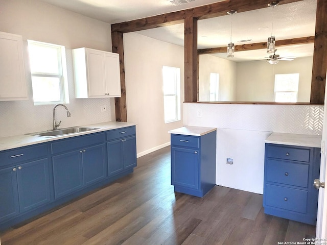 kitchen featuring dark wood finished floors, beam ceiling, decorative backsplash, blue cabinets, and a sink