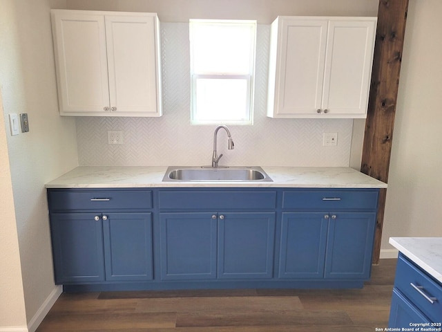 kitchen featuring blue cabinetry, white cabinets, and a sink