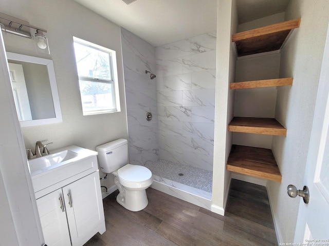 bathroom with vanity, toilet, wood finished floors, and a stall shower