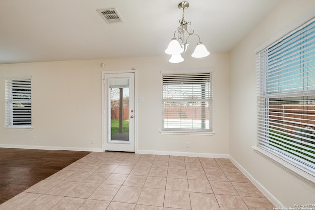 unfurnished room featuring a wealth of natural light, visible vents, baseboards, and an inviting chandelier