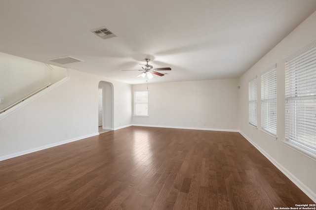 interior space with visible vents, dark wood-type flooring, baseboards, arched walkways, and a ceiling fan