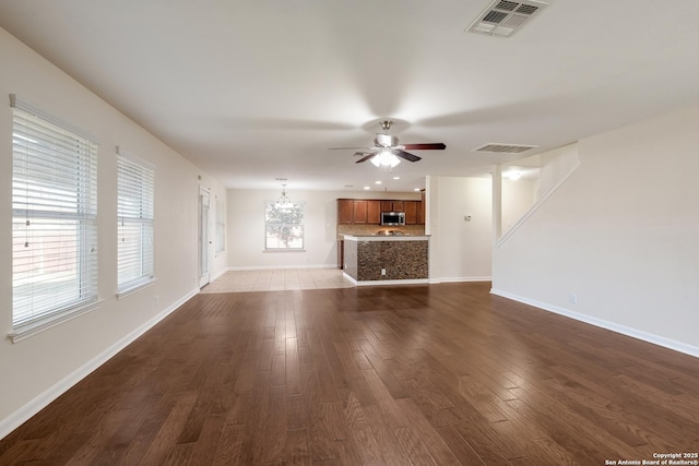 unfurnished living room with baseboards, visible vents, and dark wood-style flooring