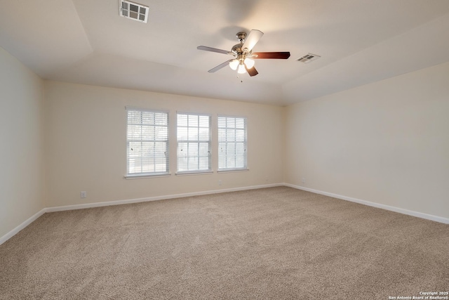 carpeted spare room featuring baseboards, visible vents, and ceiling fan