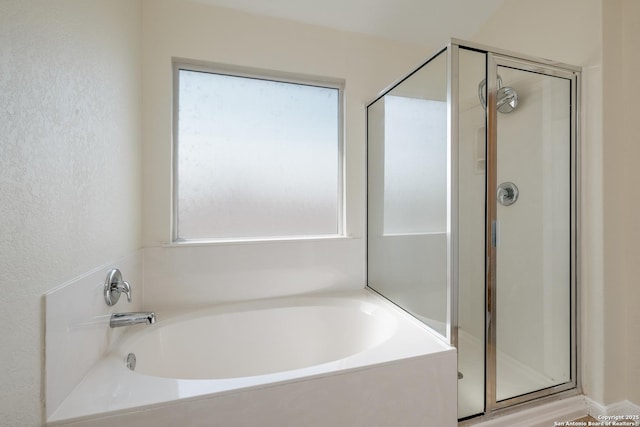 full bathroom with a bath, a shower stall, and a textured wall