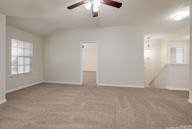 carpeted spare room featuring vaulted ceiling, baseboards, and ceiling fan