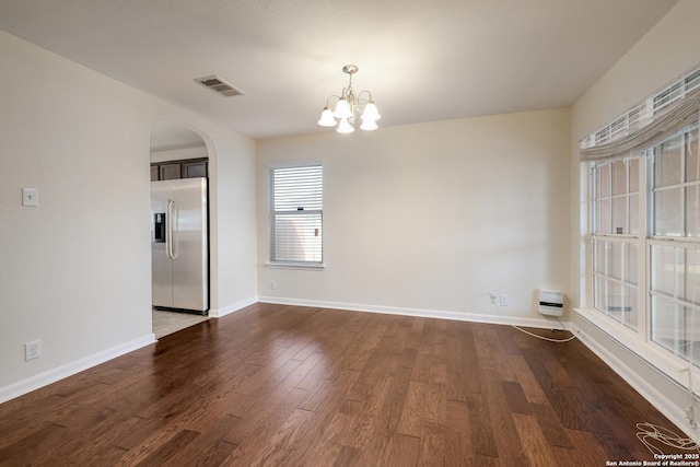 unfurnished dining area featuring visible vents, baseboards, a chandelier, arched walkways, and dark wood-style floors