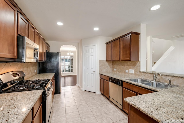 kitchen with visible vents, a sink, stainless steel appliances, arched walkways, and light tile patterned flooring