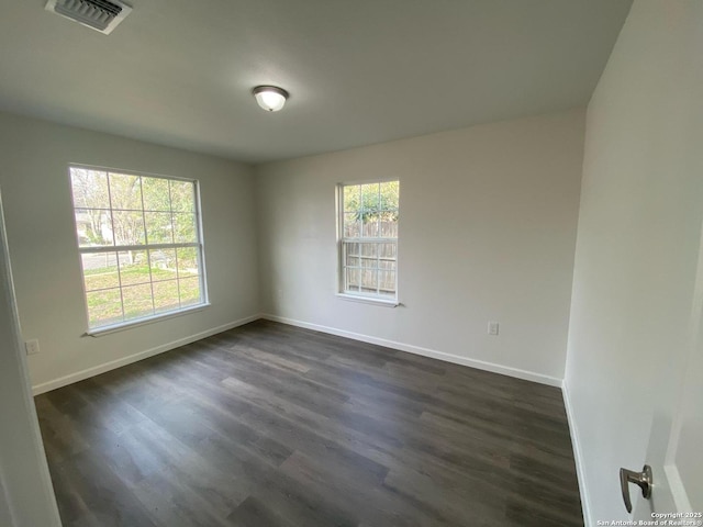 unfurnished room featuring baseboards, visible vents, and dark wood-style flooring