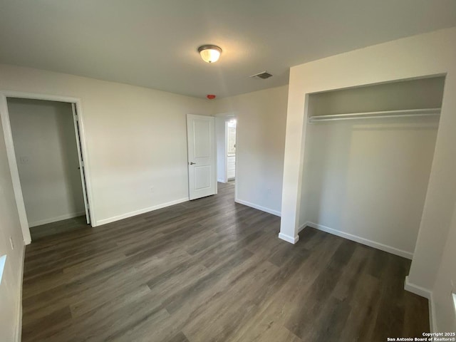 unfurnished bedroom featuring dark wood finished floors, visible vents, a closet, and baseboards