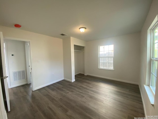 unfurnished bedroom featuring visible vents, multiple windows, and dark wood-type flooring