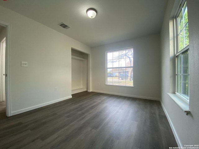 unfurnished bedroom with visible vents, baseboards, a closet, and dark wood finished floors