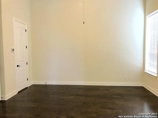 empty room with baseboards and dark wood-style flooring