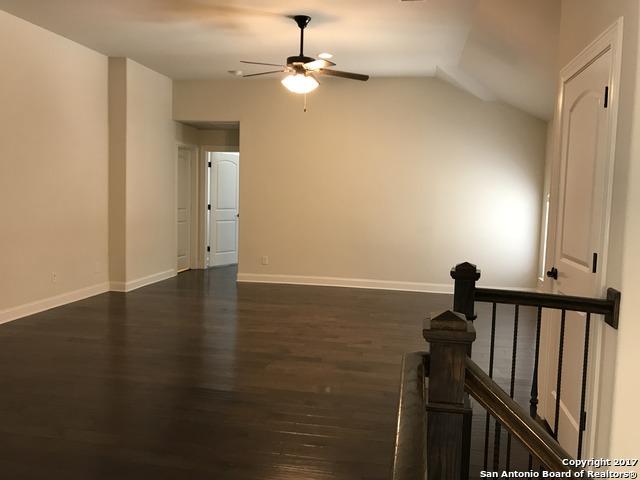 empty room with baseboards, a ceiling fan, dark wood-style flooring, and vaulted ceiling