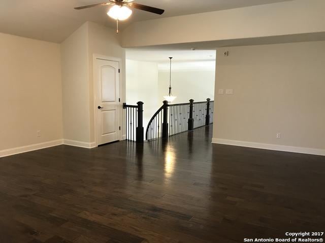 unfurnished room with baseboards, ceiling fan, and dark wood-style flooring