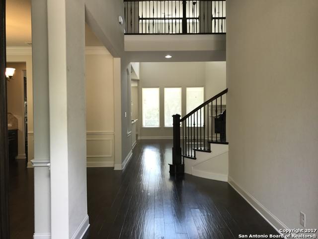 entrance foyer featuring crown molding, baseboards, stairway, ornate columns, and dark wood-style flooring