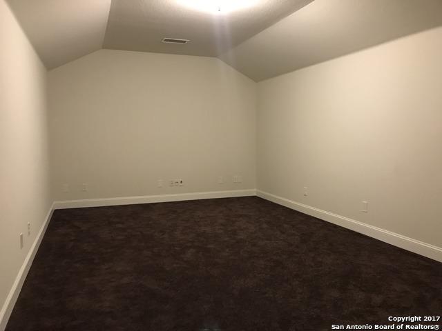 unfurnished room featuring dark colored carpet, visible vents, lofted ceiling, and baseboards