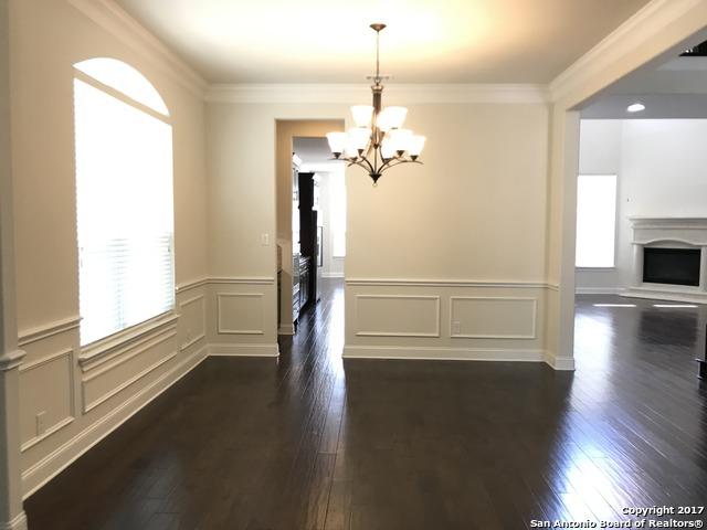 unfurnished dining area featuring crown molding, a decorative wall, a fireplace with raised hearth, and dark wood-type flooring