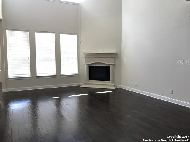 unfurnished living room featuring baseboards, wood finished floors, and a fireplace with raised hearth