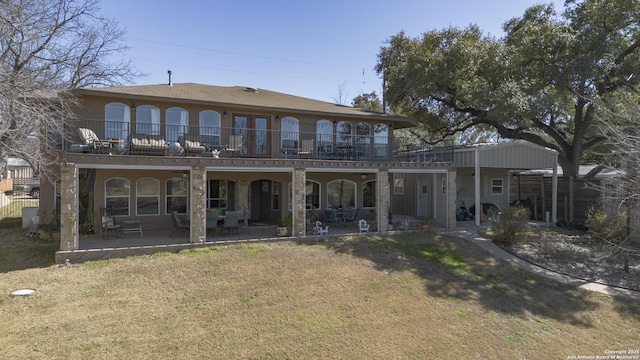 rear view of property with stucco siding, fence, a yard, a balcony, and a patio area