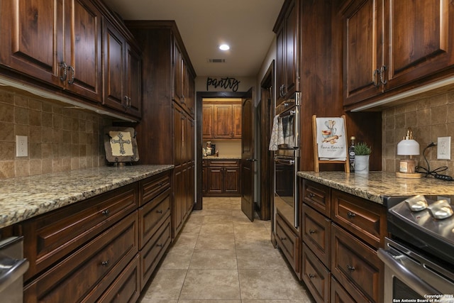 kitchen featuring light tile patterned floors, light stone countertops, visible vents, stainless steel range with electric stovetop, and tasteful backsplash