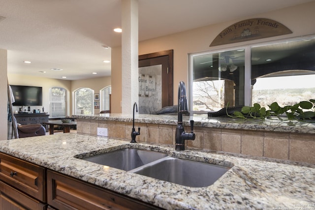 kitchen with a sink, light stone counters, and recessed lighting