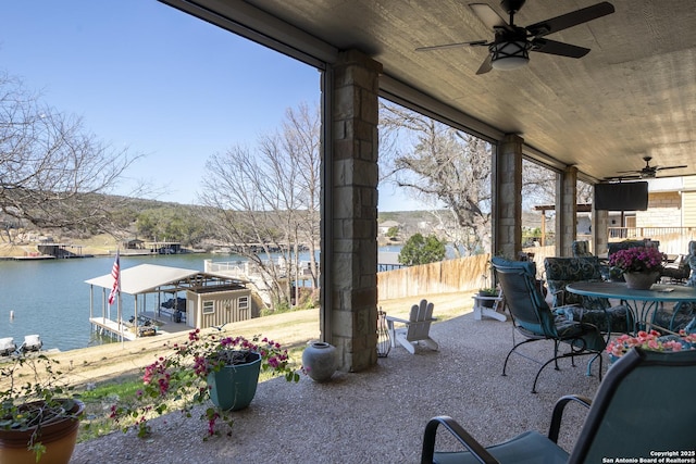 view of patio with fence, a water view, and ceiling fan