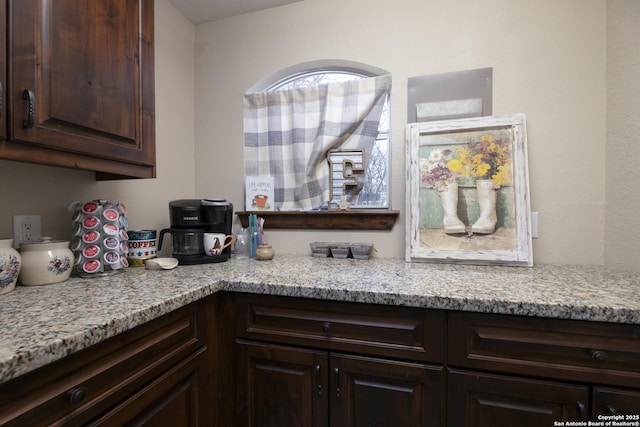 kitchen featuring dark brown cabinetry and light stone counters