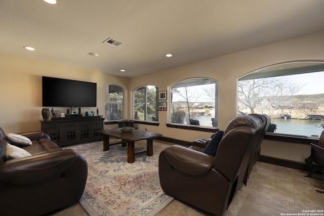 living area with tile patterned flooring, visible vents, a water view, recessed lighting, and a textured ceiling