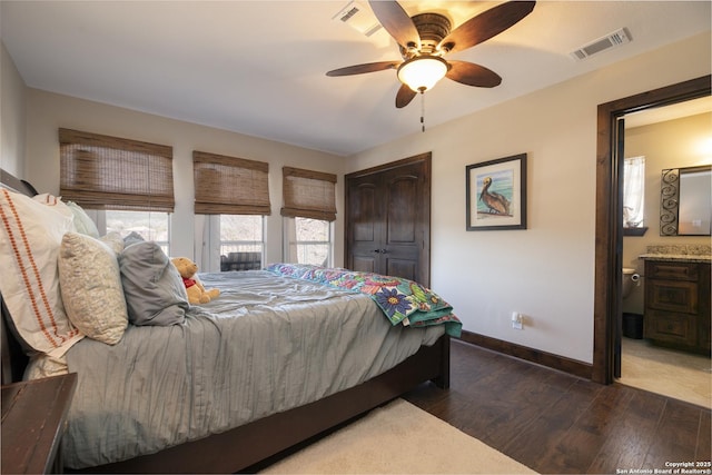 bedroom with visible vents, ensuite bathroom, wood finished floors, baseboards, and ceiling fan