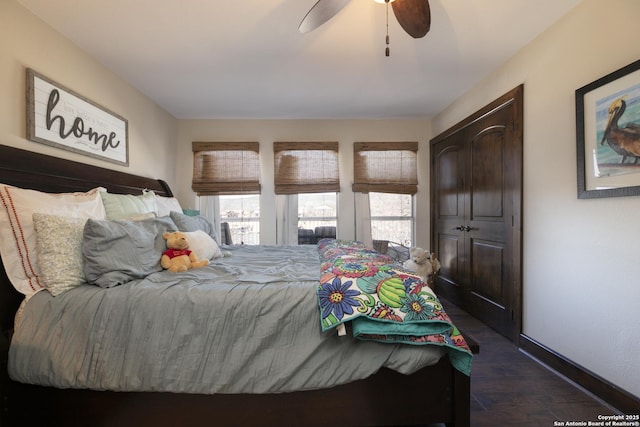 bedroom featuring baseboards, a ceiling fan, and dark wood-style flooring