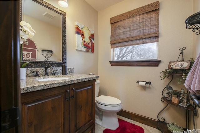 half bathroom with vanity, baseboards, visible vents, tile patterned floors, and toilet