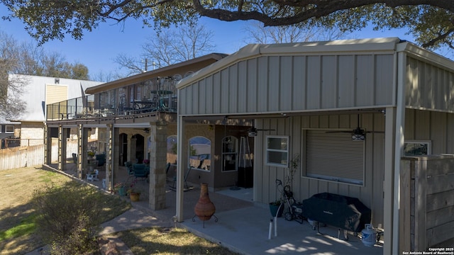 rear view of house with a patio, a balcony, a ceiling fan, and board and batten siding