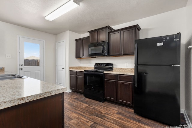 kitchen featuring black appliances, a sink, dark brown cabinetry, light countertops, and dark wood-style flooring