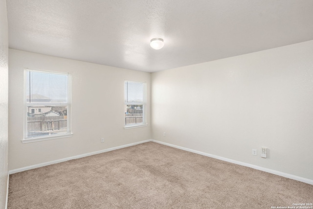 carpeted empty room featuring a wealth of natural light and baseboards