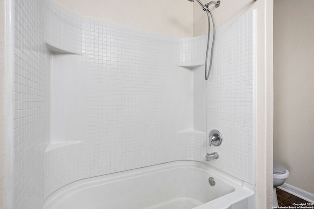 bathroom featuring toilet, shower / bath combination, and baseboards