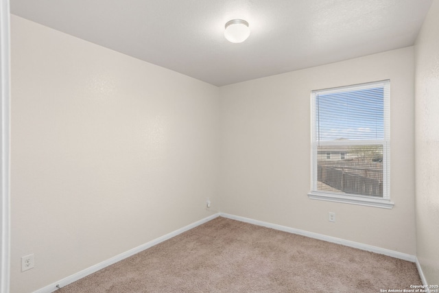 spare room with light carpet and baseboards