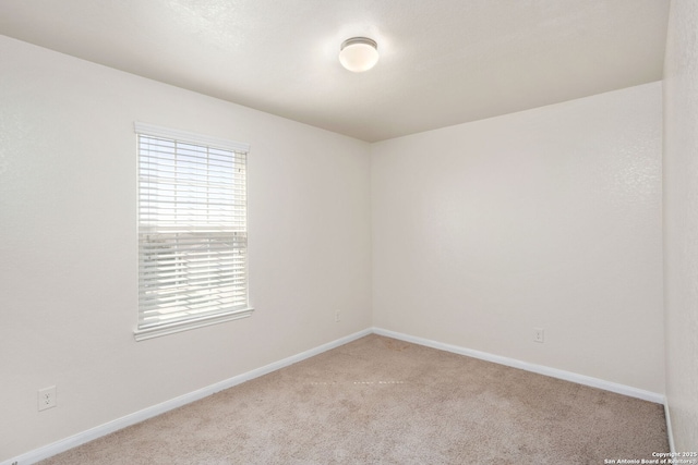 unfurnished room featuring carpet and baseboards