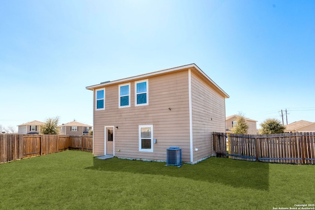 rear view of house with a fenced backyard and a yard