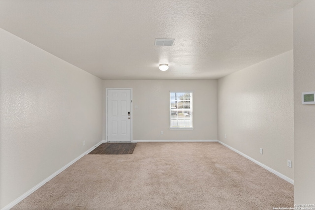 unfurnished room featuring visible vents, carpet floors, a textured ceiling, and baseboards