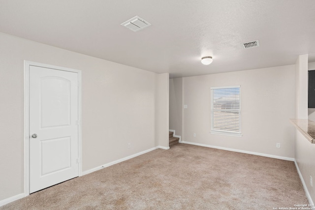 carpeted spare room with stairway, baseboards, visible vents, and a textured ceiling