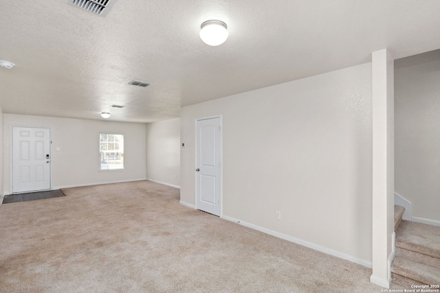 carpeted spare room with visible vents, baseboards, a textured ceiling, and stairway