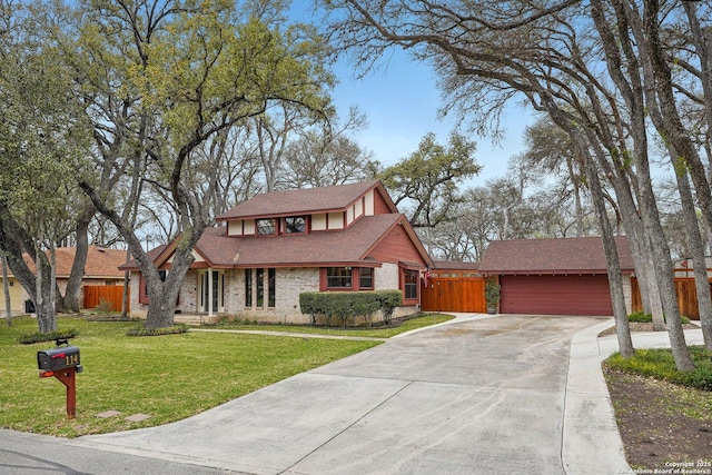 tudor-style house with brick siding, concrete driveway, a front lawn, and fence