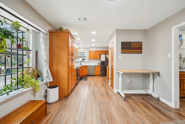 kitchen with visible vents, light countertops, light wood-type flooring, fridge with ice dispenser, and stainless steel dishwasher