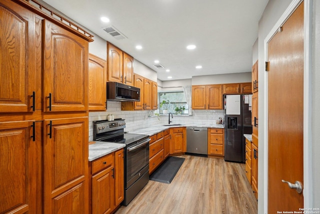 kitchen featuring visible vents, a sink, light wood-style floors, appliances with stainless steel finishes, and tasteful backsplash