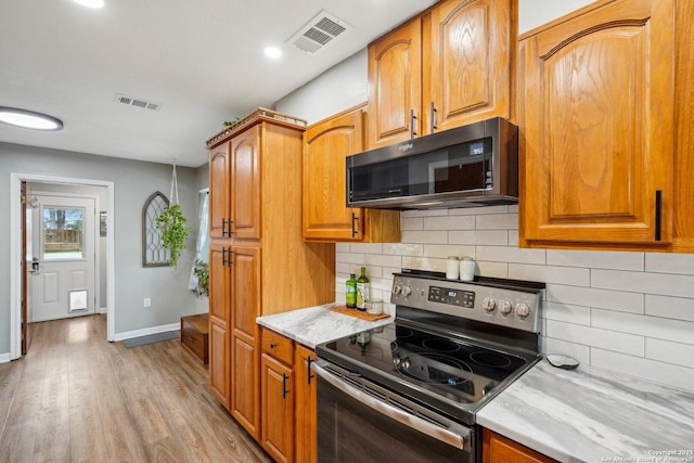 kitchen with visible vents, light wood-style flooring, stainless steel range with electric cooktop, and baseboards