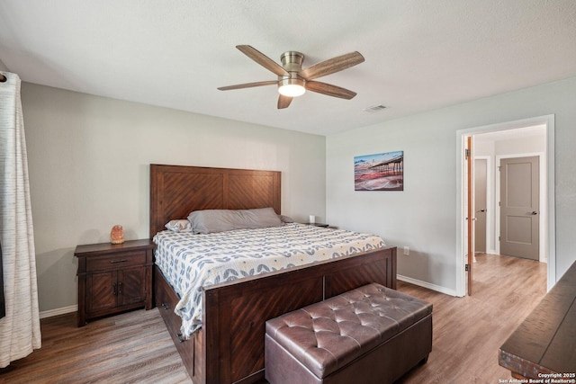 bedroom with light wood-type flooring, visible vents, baseboards, and ceiling fan