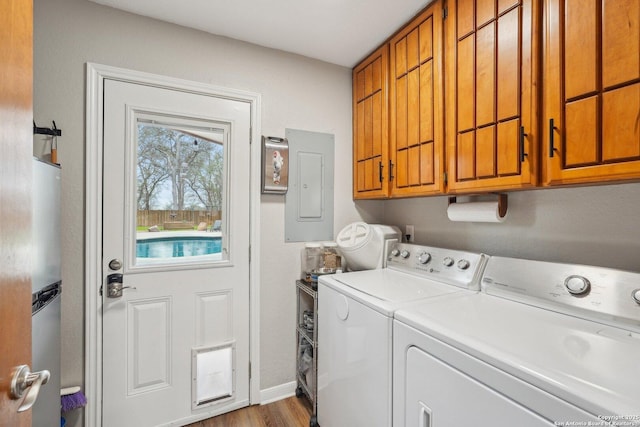 clothes washing area with baseboards, electric panel, wood finished floors, cabinet space, and separate washer and dryer