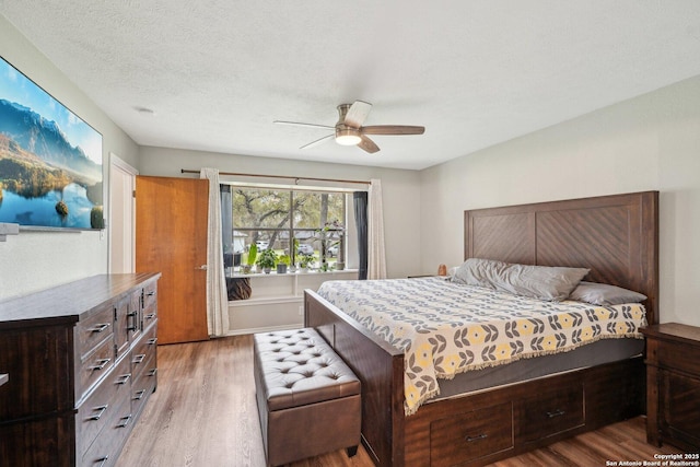 bedroom featuring ceiling fan, wood finished floors, and a textured ceiling