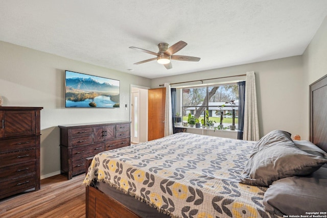 bedroom featuring baseboards, a textured ceiling, wood finished floors, and a ceiling fan